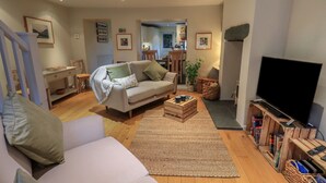 A living room with a sofa, coffee table, TV, and wooden bookshelves.