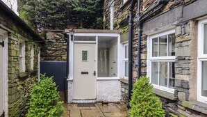 A stone house with a white door, a small garden with potted plants, and a stone pathway.