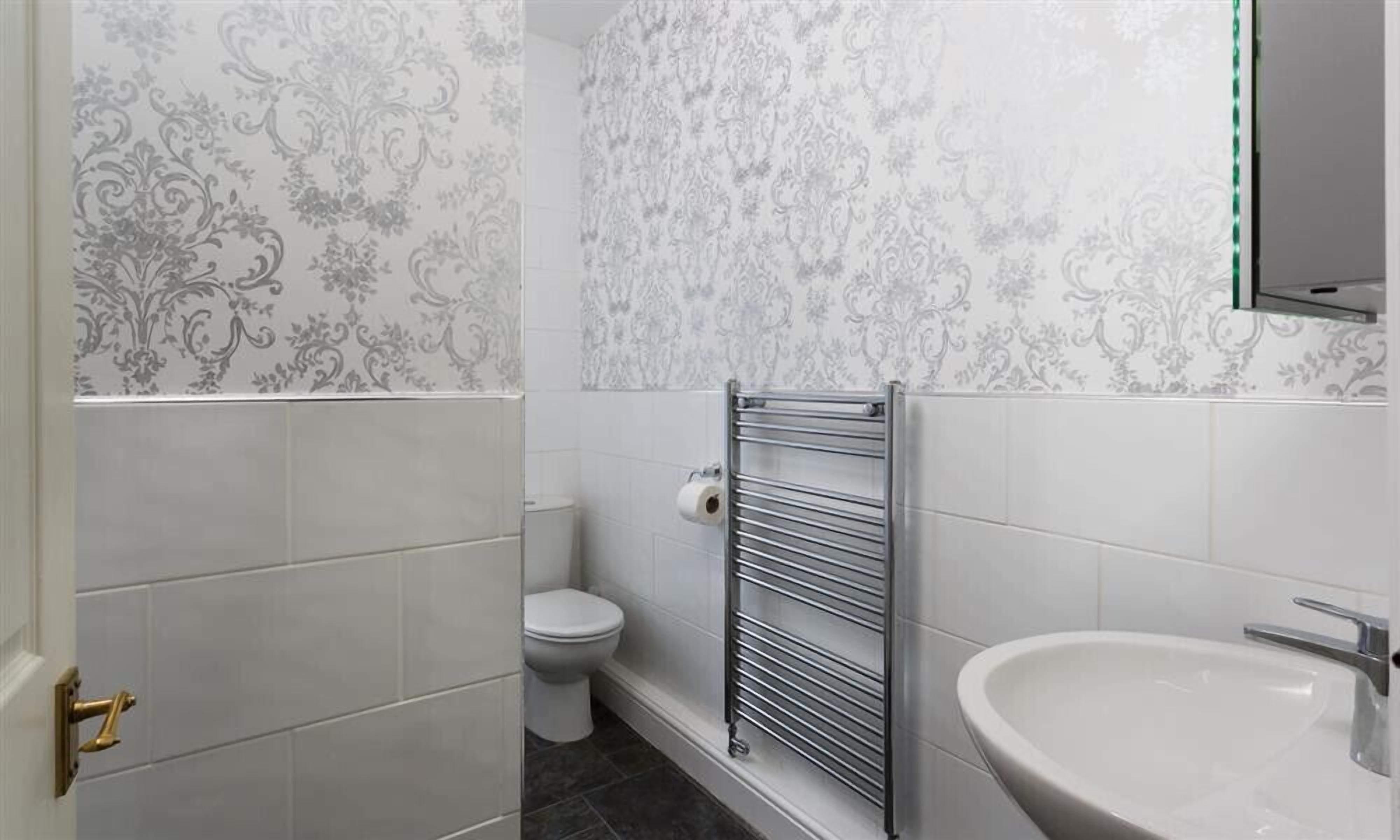 A bathroom with a toilet, a towel rack, and a sink.