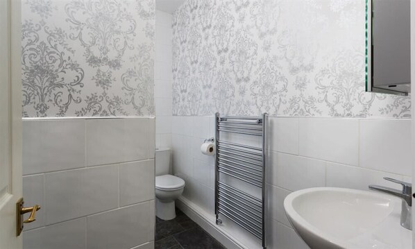 Une salle de bain équipée de toilettes, d’un porte-serviettes et d’un lavabo.