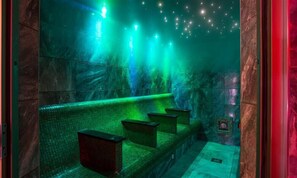 A dimly lit, green-hued room with a stone wall and a tiled floor. - The Blithe Hare (Windermere)