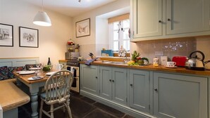 Una cocina con una mesa de comedor, sillas, un hervidor y varios electrodomésticos.