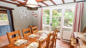 Une salle à manger avec une table en bois dressée pour six personnes, entourée de chaises en bois.