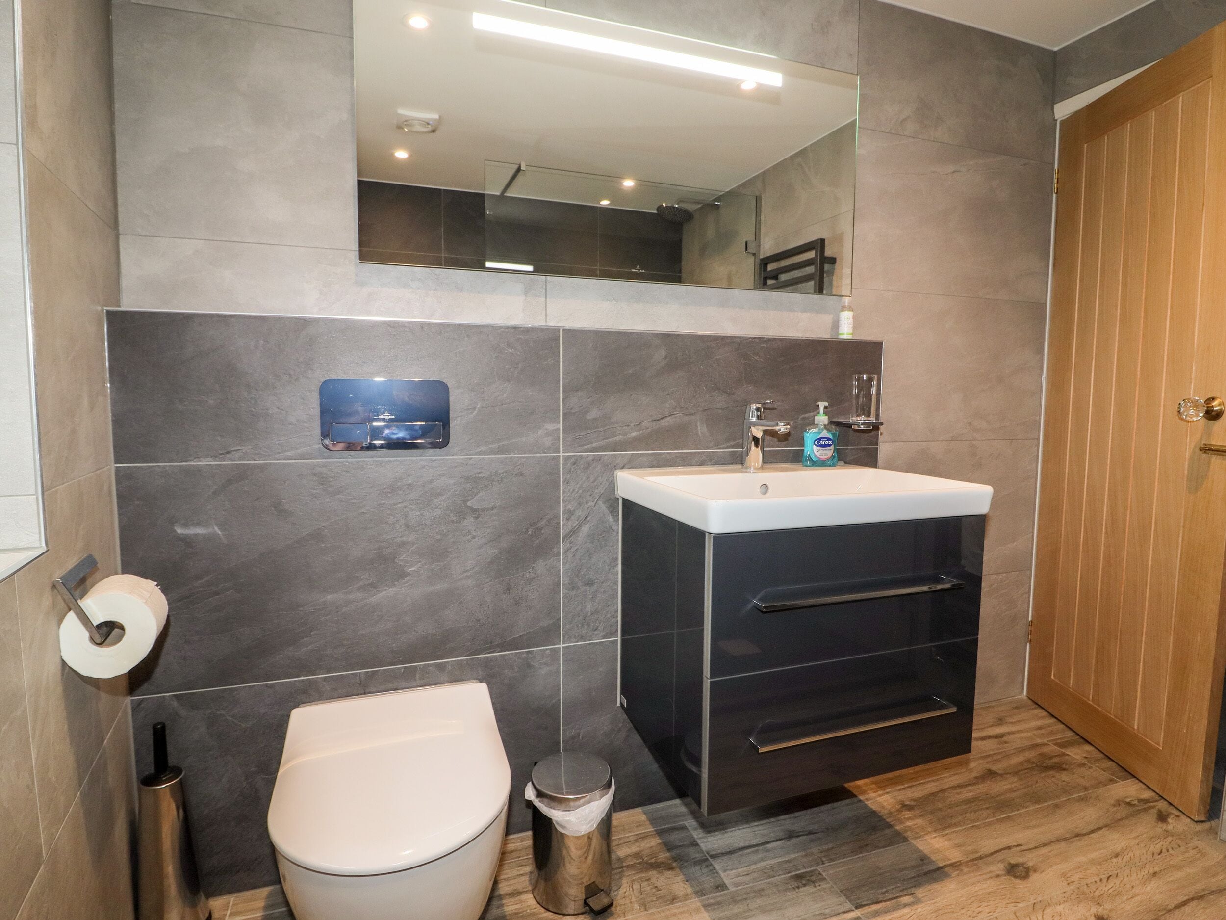 A modern bathroom with a toilet, sink, and mirror.