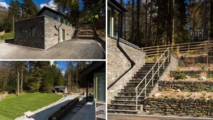 A modern stone house with a stone staircase and a small wooden structure in the yard. - Tall Trees (Windermere)