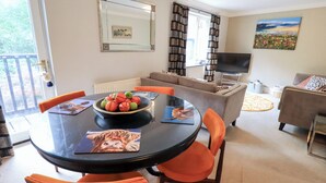 A dining area with a round table, orange chairs, and a bowl of fruit. - Ghyll Heights (Ambleside)