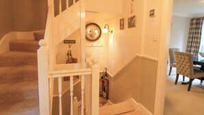 A staircase with a white railing, a wall-mounted mirror, and a 'Boot Mat' sign. - Ghyll Heights (Ambleside)