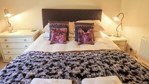 A neatly made bed with two decorative pillows, a dark headboard, and bedside lamps on either side. - Ghyll Heights (Ambleside)