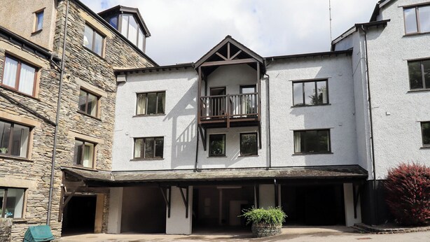 A two-story building with a central balcony, stone facade, and a covered entrance area. - Ghyll Heights (Ambleside)