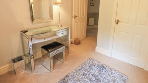 A bathroom with a glass vanity, a mirror, a lamp, and a rug. - Ghyll Heights (Ambleside)