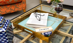 A glass coffee table with a book, glasses, and a wine glass. - Pippin Cottage (Keswick)