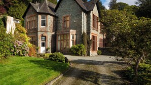 A large stone building with multiple windows and a well-maintained lawn. - Brunt How (Ambleside)