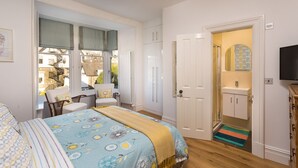 A bedroom with a bed, a chair, a wardrobe, a door leading to a bathroom, and a television.