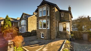 A stone house with a prominent bay window, a front porch, and a driveway leading to a garage.