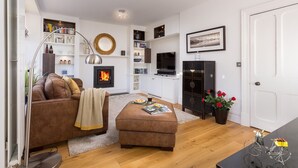 A modern living room with a fireplace, leather sofas, a coffee table, and a bookshelf.