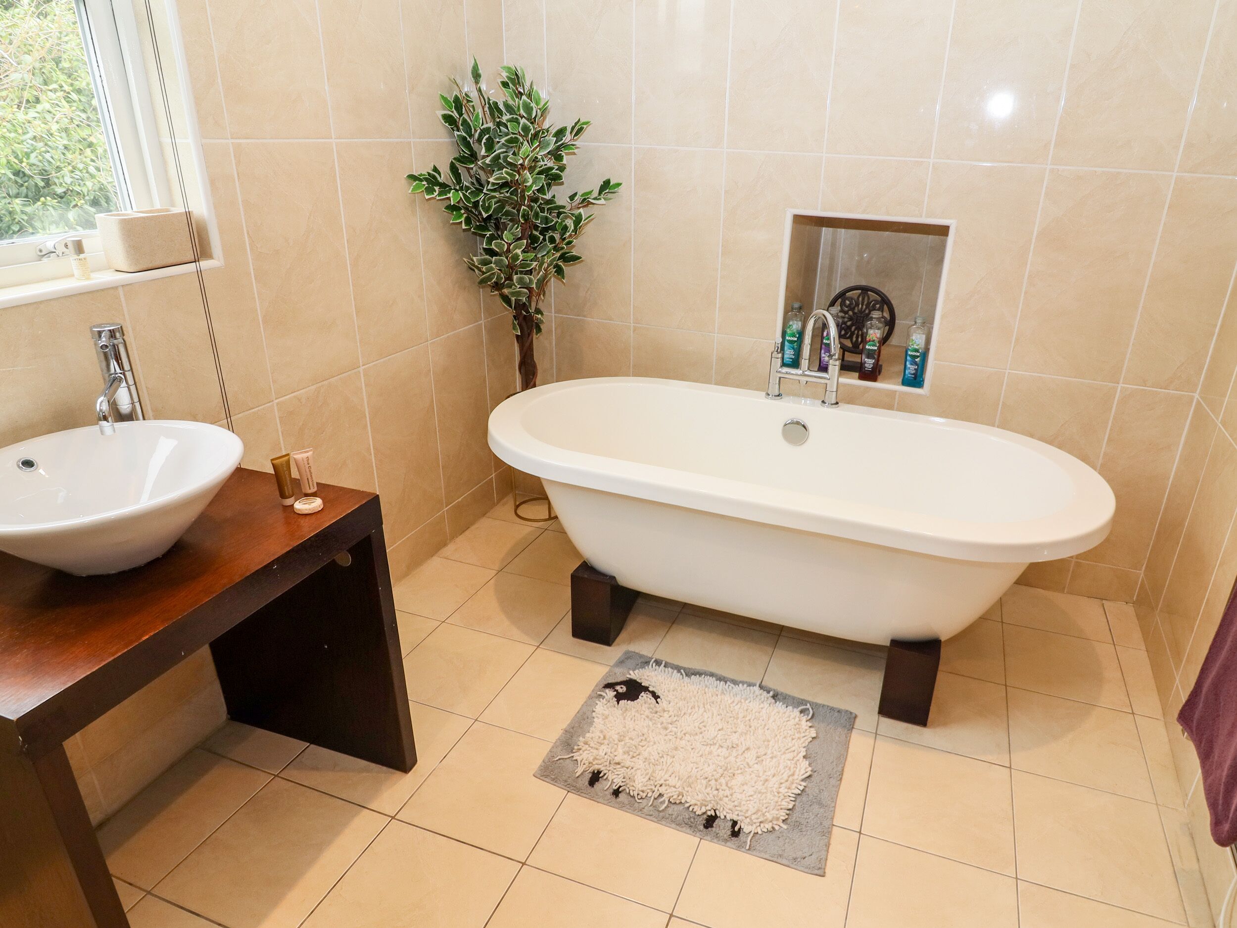 A bathroom with a freestanding bathtub, a sink, and a small potted plant.