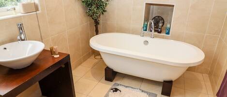 A bathroom with a freestanding bathtub, a sink, and a small potted plant.