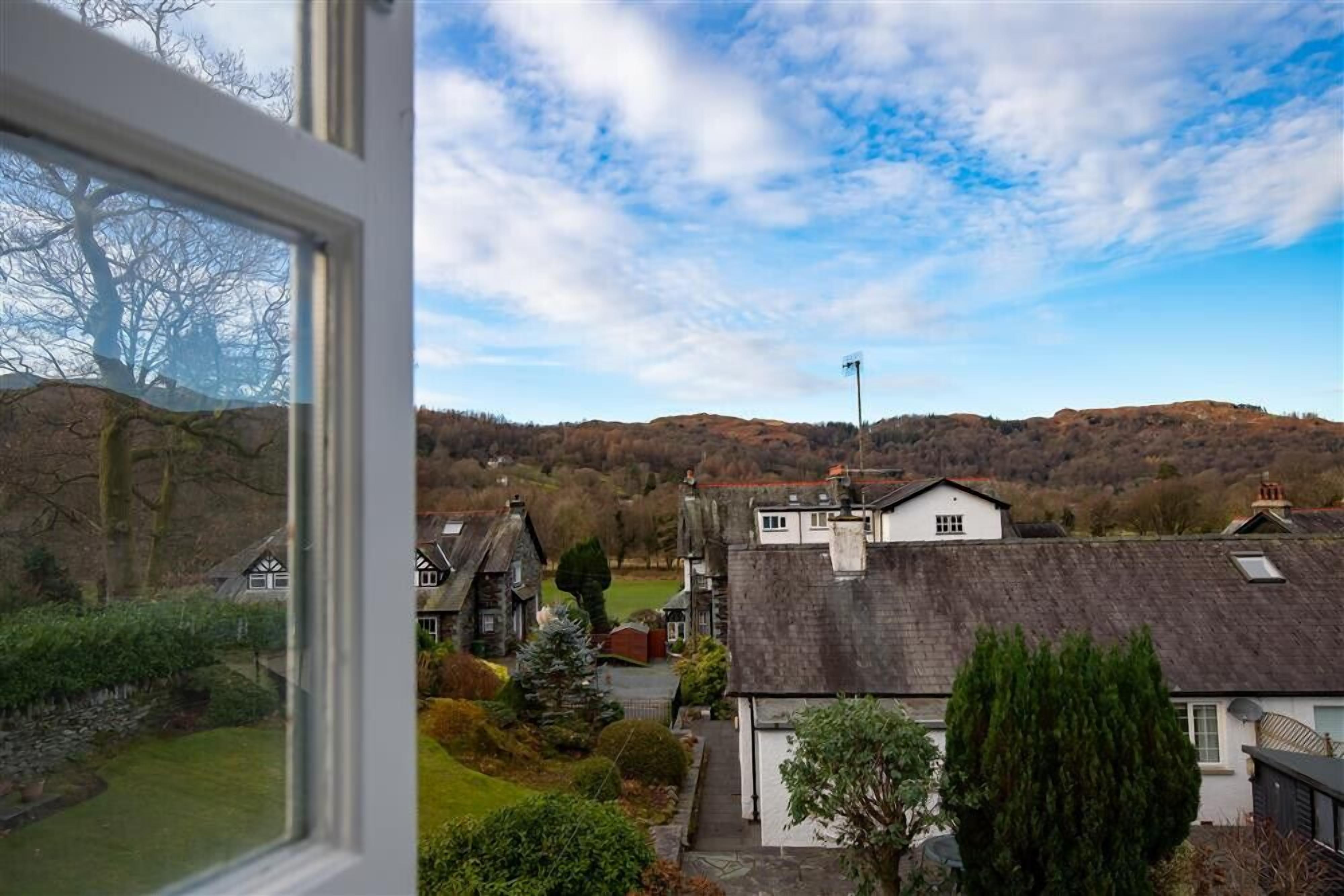 A residential area with houses, a clear sky, and a hilly landscape in the background.