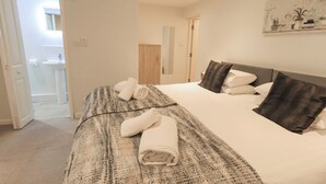 A hotel room with a bed, a bathroom visible through an open door, and a painting on the wall.