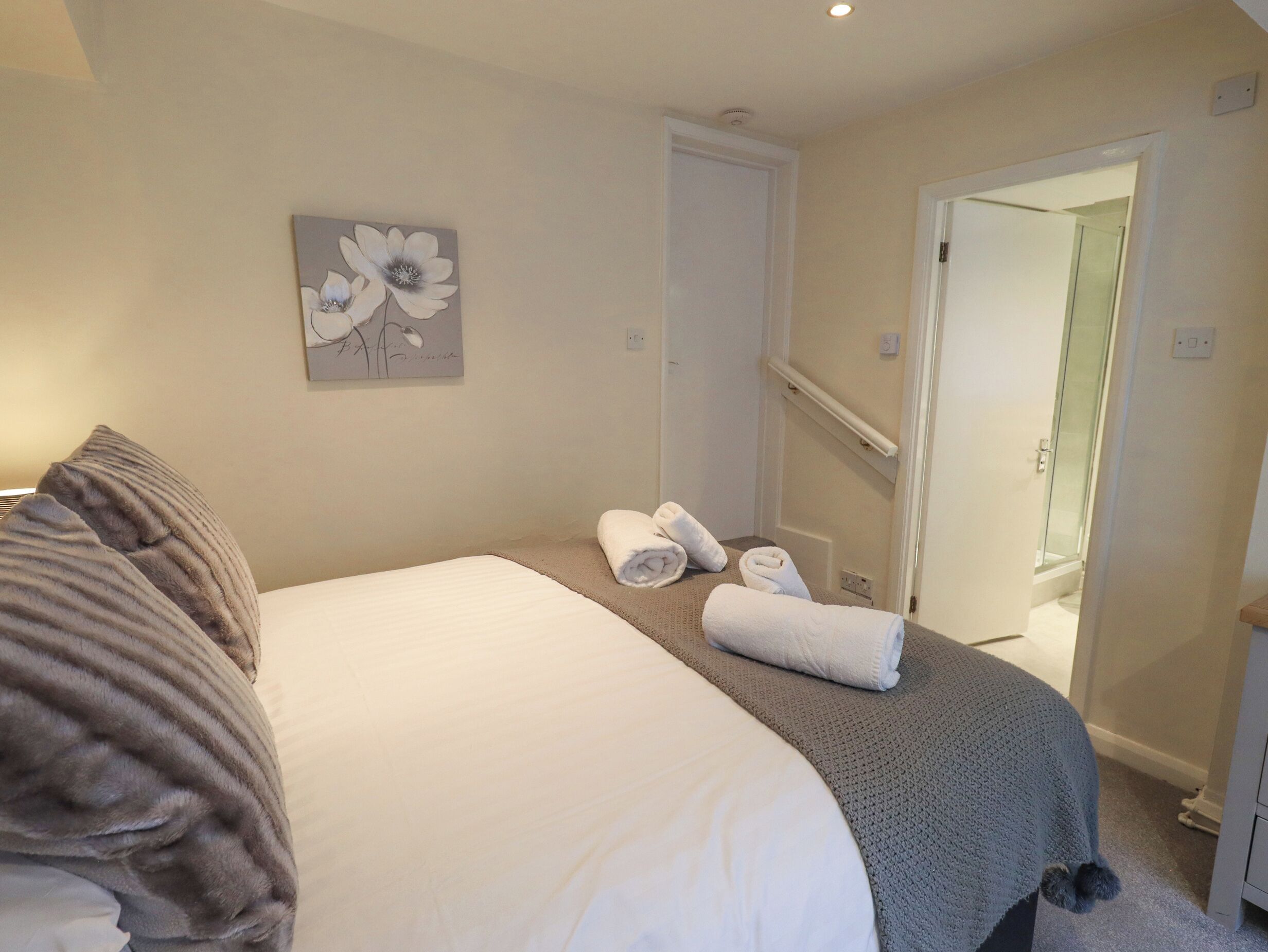 A bedroom with a bed, pillows, a towel, and a painting on the wall.