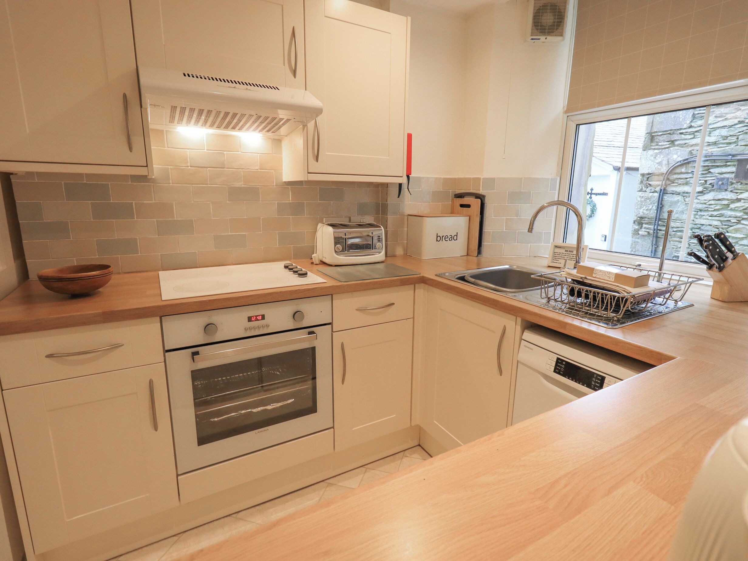 A modern kitchen with a built-in oven, a toaster, and a bread box on the counter.