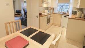 A modern kitchen with white cabinets, a built-in oven, a dishwasher, and a window providing natural light.