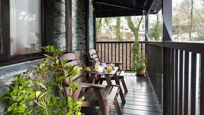 A wooden deck with a table and chairs, a potted plant, and a stone wall.