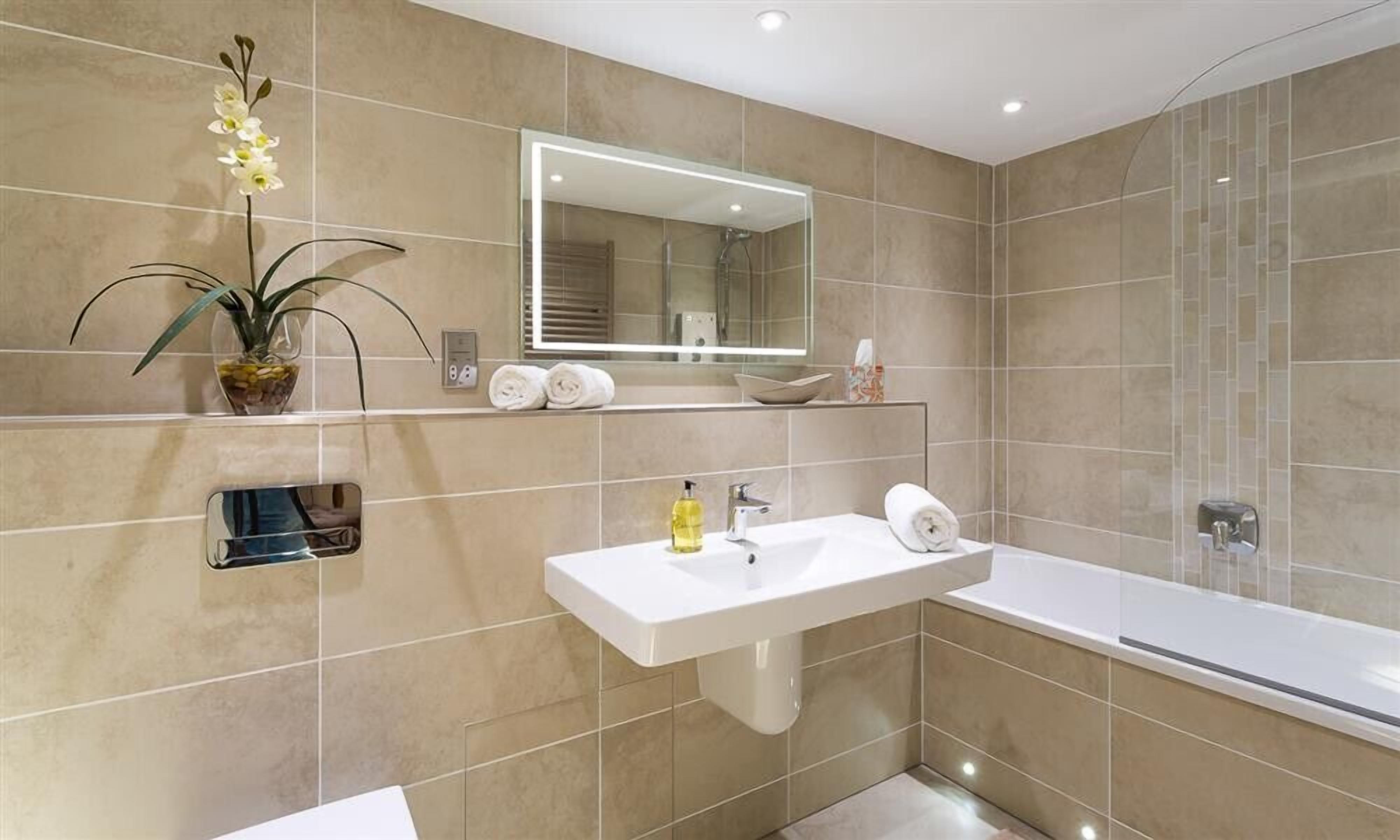 A modern bathroom with a white sink, a mirror, and a bathtub.