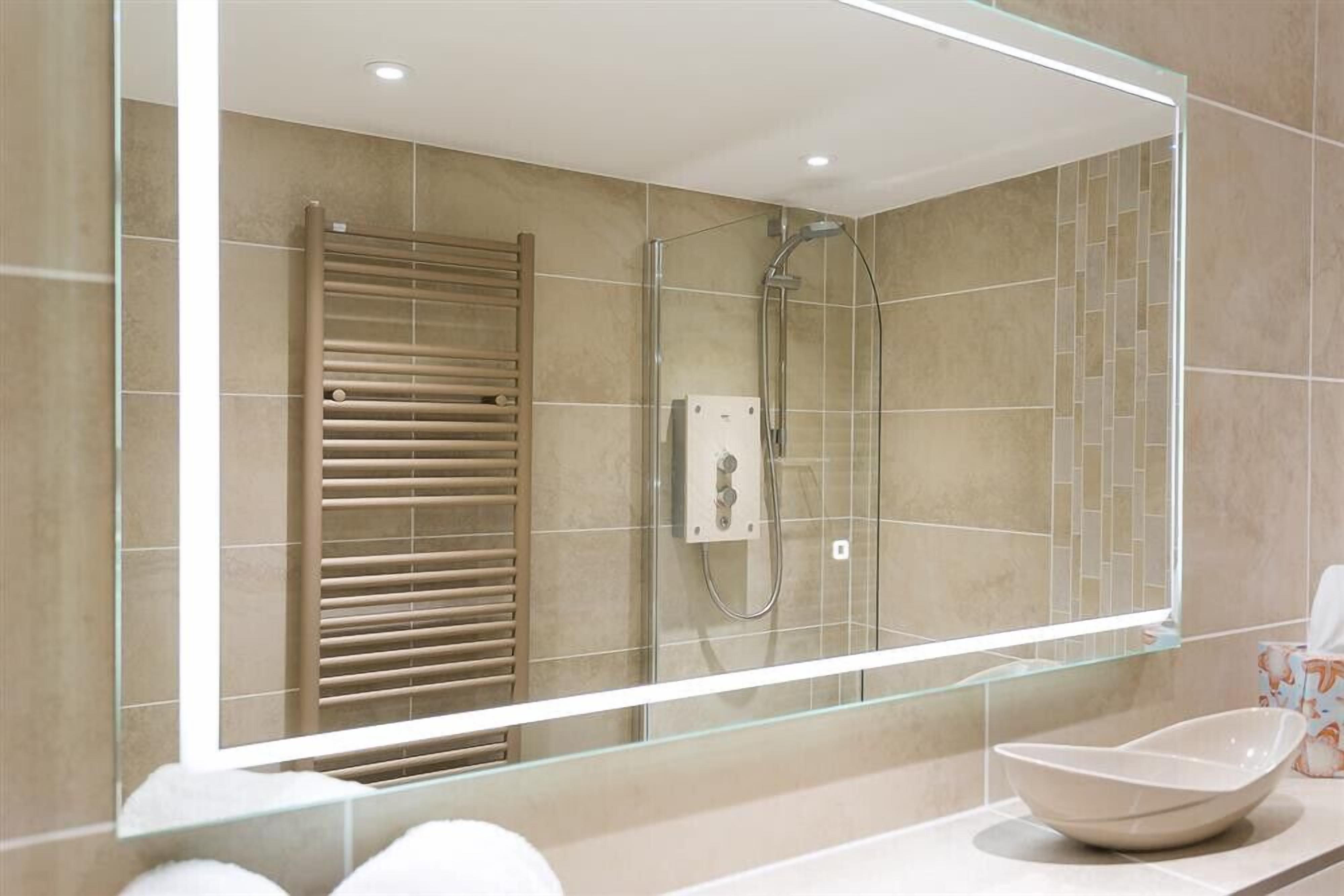 A modern bathroom with a glass-enclosed shower, a towel rack, and a bowl sink.