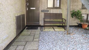 A stone building with a wooden door, a bench, and a sign reading "Puddleduck". - Puddleduck (Ambleside)