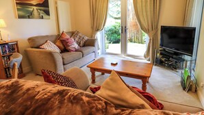 A living room with a sofa, a coffee table, a bookshelf, and a TV. - Puddleduck (Ambleside)