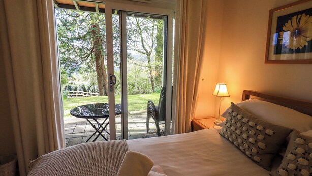A hotel room with a bed, a table, and a chair outside the door. - Puddleduck (Ambleside)