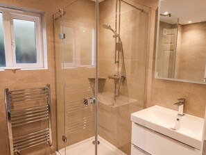 A modern bathroom with a glass-enclosed shower, a white sink, and a towel rack. - Garden House (Ambleside)