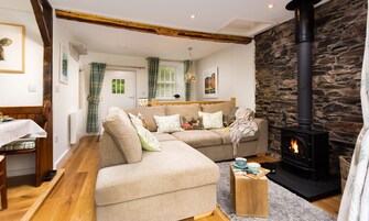 Una sala de estar acogedora con chimenea de piedra, un sofá y un comedor con mesa y sillas.