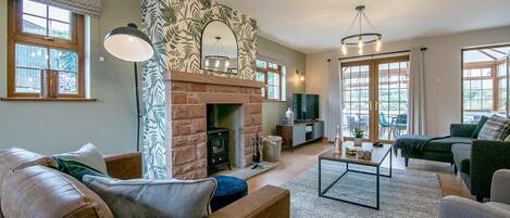 A cozy living room with a fireplace, comfortable seating, and large windows.
