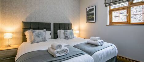 A hotel room with a large bed, two bedside tables, a window with a view, and a framed picture on the wall.