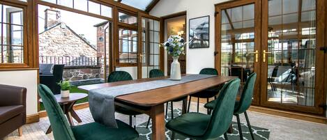 A dining area with a wooden table, green upholstered chairs, and a vase with flowers.