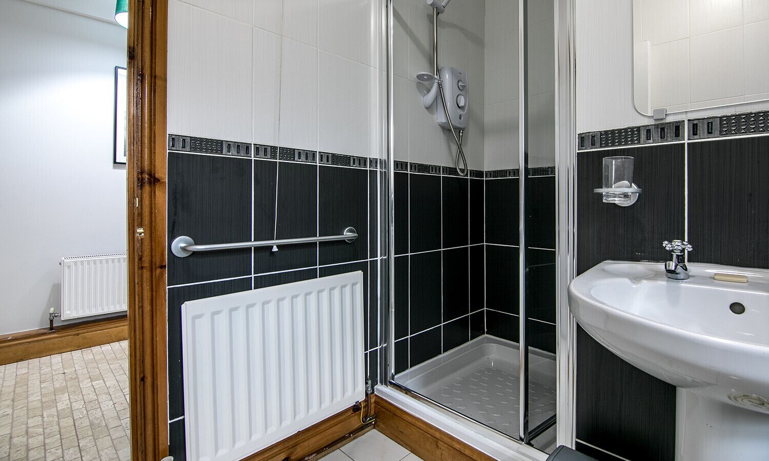 A bathroom with a shower, a sink, and a white radiator.