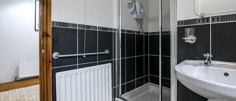 A bathroom with a shower, a sink, and a white radiator.