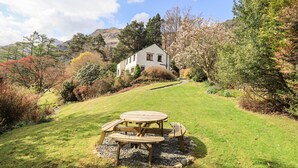 Uma casa com jardim e mesa para piquenique.