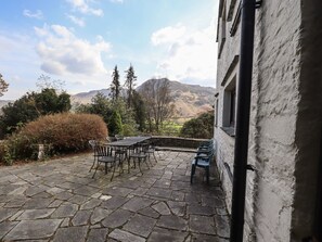 A stone patio with a table and chairs, overlooking a mountainous landscape.