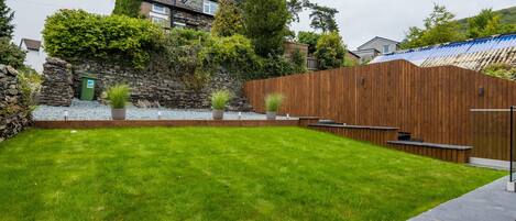 A well-maintained backyard with a grassy lawn, a stone wall, and a wooden fence.