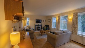 A cozy living room with a sofa, a coffee table, and a TV. - Holly Cottage (Ambleside)