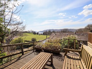 A wooden deck with benches overlooking a green field and distant hills. - Oak Bank (Windermere)