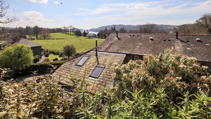 Una casa con techo inclinado, tragaluces y vistas a un campo verde y montañas a lo lejos.