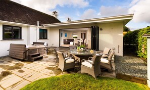 A patio area with wicker furniture, a barbecue, and a view into the house. - Glebe Holme (Windermere)