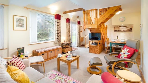 Un salon confortable avec un canapé, une table basse, un téléviseur et un escalier en bois.