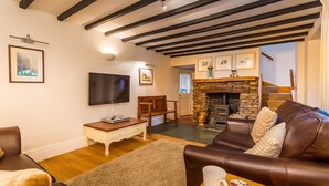Una sala de estar acogedora con chimenea, televisor de pantalla plana y un sofá de cuero marrón confortable.