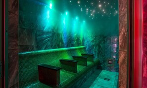Un baño tenuemente iluminado, con baldosas, un banco y un espejo.