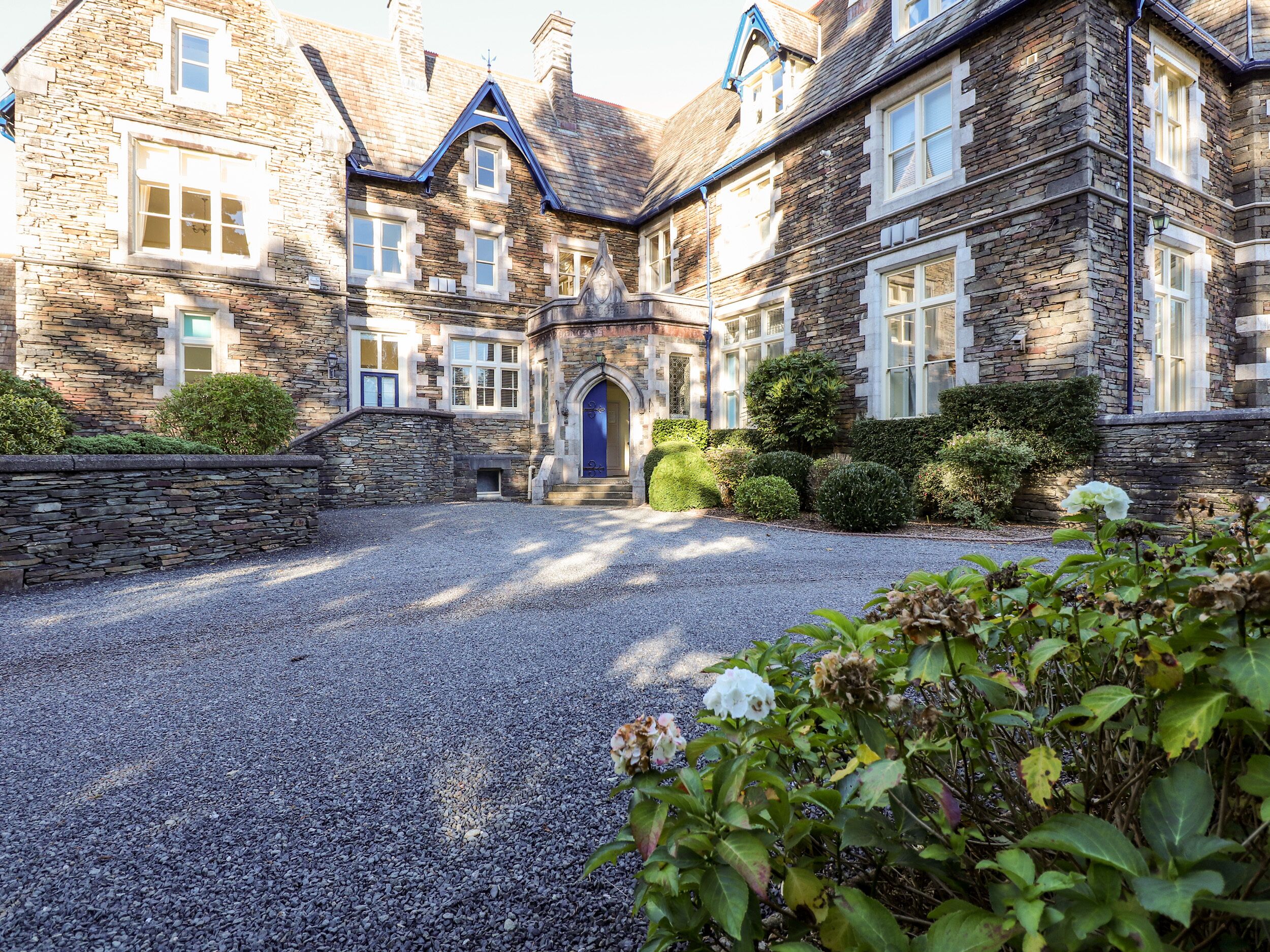 A stone building with a gravel driveway and a blue door.